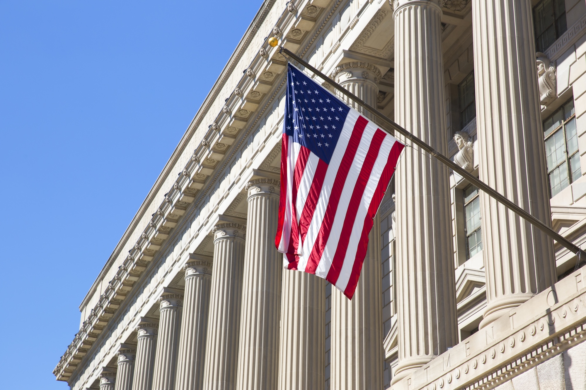 Government building with American flag representing public administration and civic service. Professional government building with classical architecture showcasing modern public administration and government operations