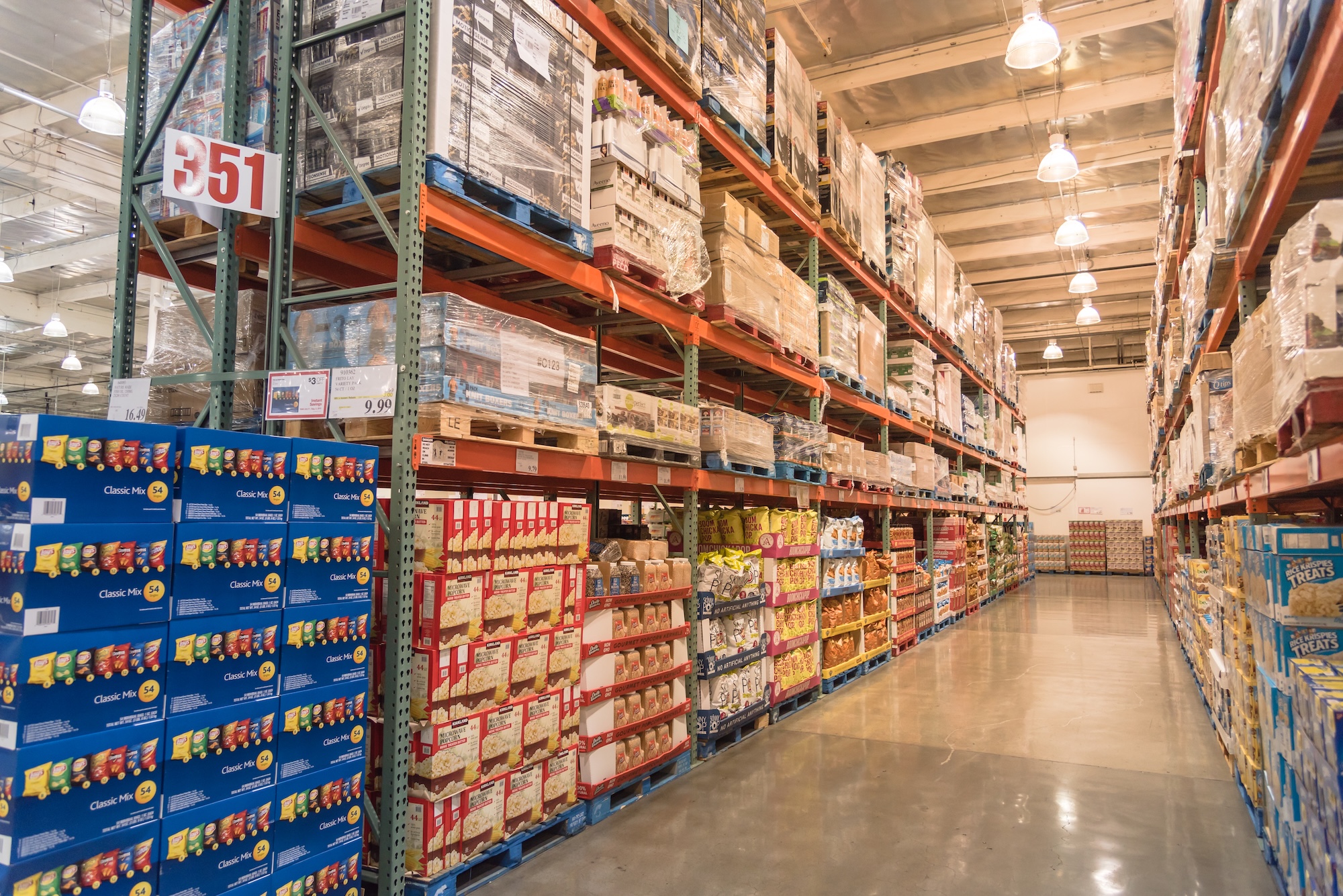 Non-durable goods warehouse with consumables and packaged products Large-scale distribution warehouse with industrial shelving storing non-durable goods including food products, snacks, and packaged consumables for wholesale distribution operations