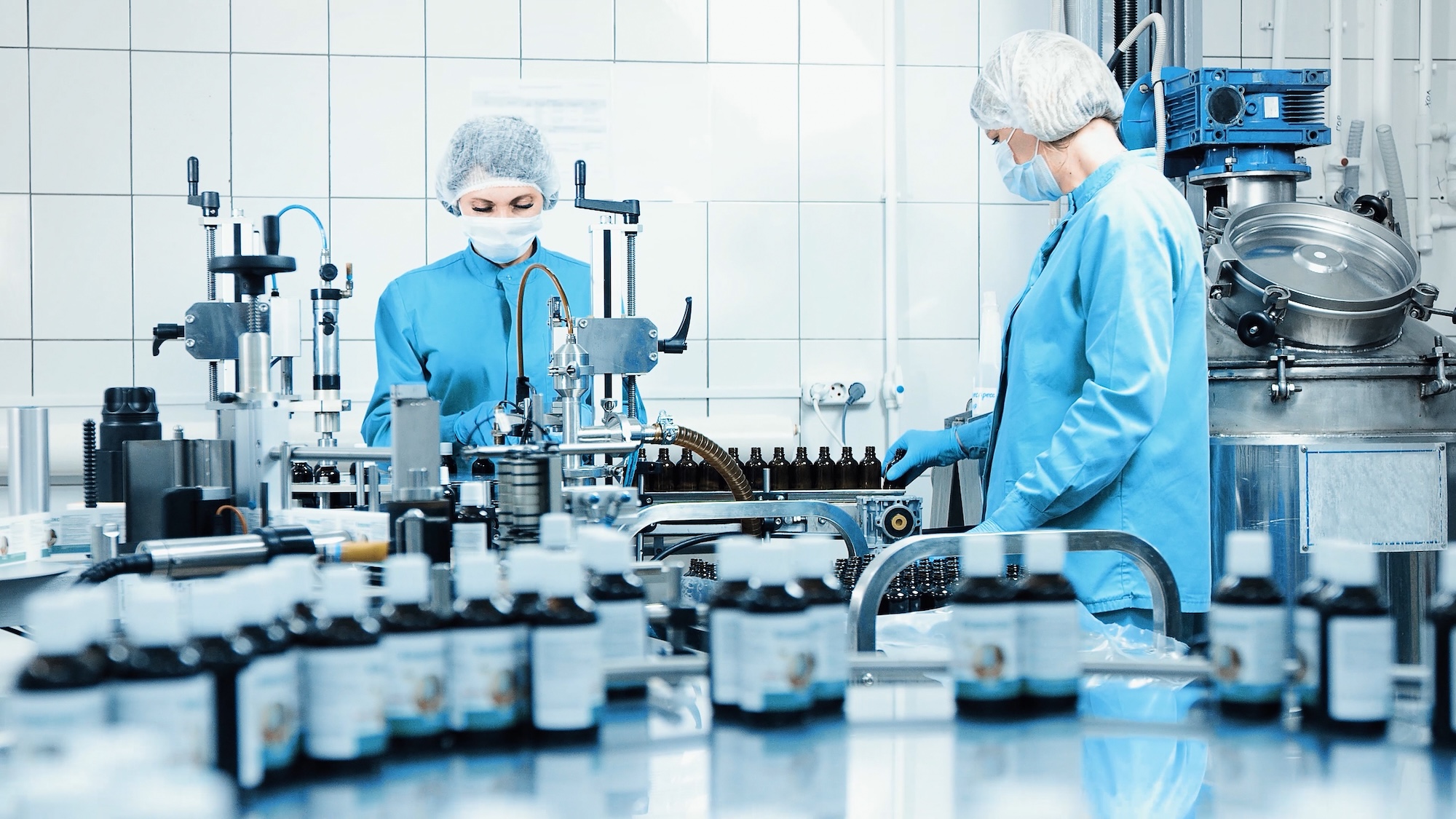 Cleanroom workers in protective suits assembling medical devices and pharmaceuticals in controlled manufacturing environment with strict quality standards